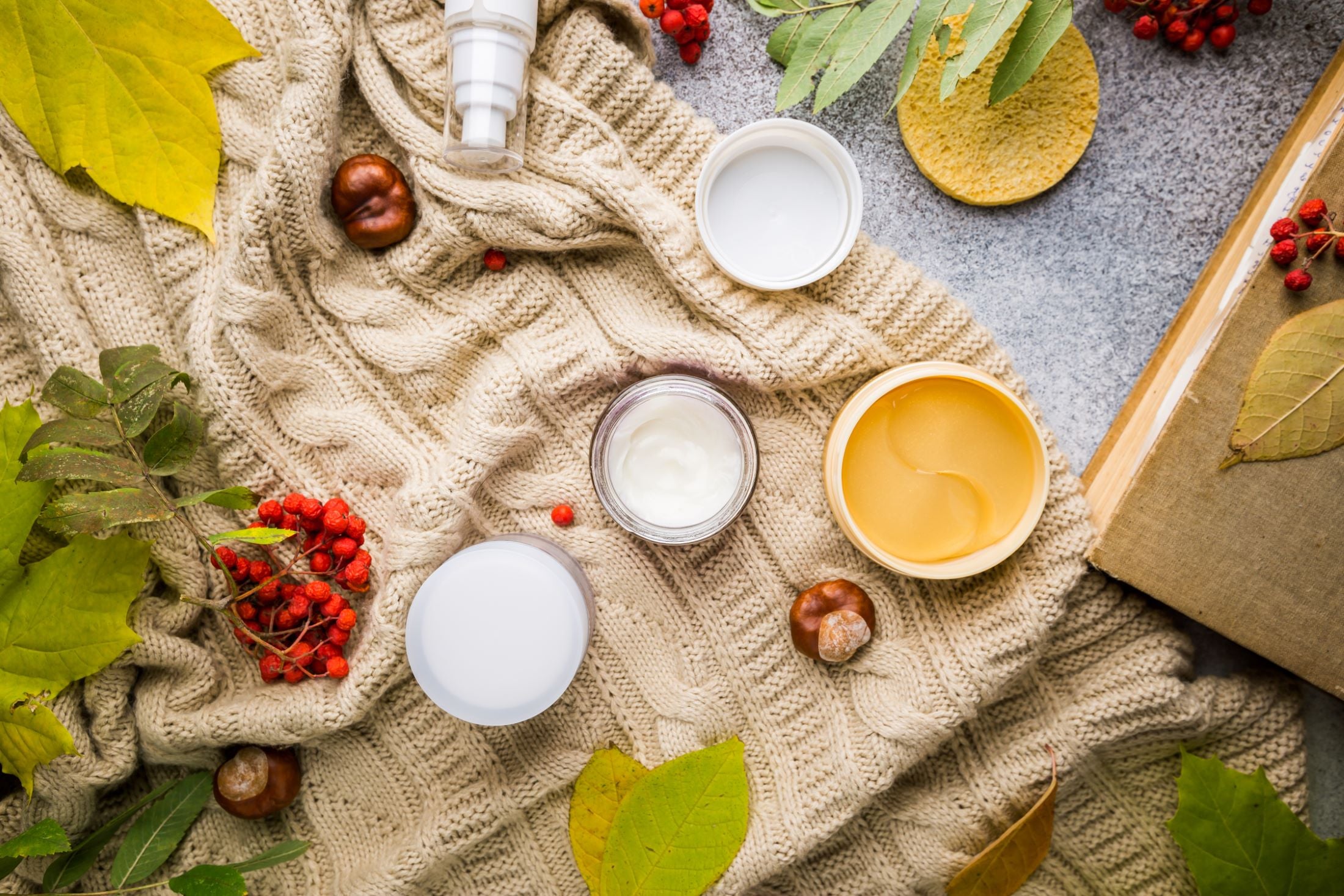 Cosmetic products on a textured surface with leaves and berries